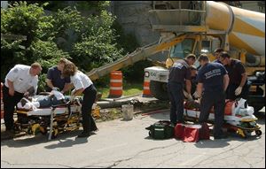 Two city workers are treated on Main Street before they are taken to the hospital. The workers were replacing the sidewalk near the Sports Arena when a rusty pole 'just plopped over,' another worker said.