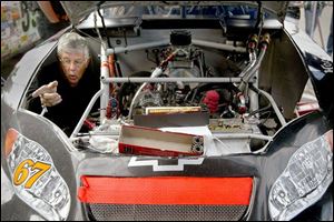 Harold Eaatmon works inside the engine compartment of Jason Jarrett's car in the pits before yesterday's ARCA event.