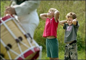 Cousins Emma Reed and Brandon Oatman hold their ears as a cannon is fired during Fourth of July events at Fort Meigs.
