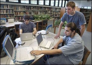 Ethan Wilke, 19, seated from left, and Rob Bathurst work on school computers under the supervision of Don Hertzfeld.
