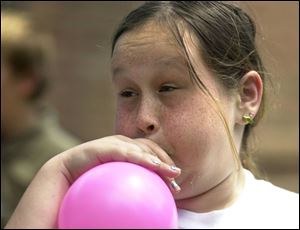 NBR wacky01p 01- 07/01/04 -Mary Smothers, 12, of Toledo, works hard to inflate her balloon for a event during Wacky Teen Olympics held at the Holland branch library Thursday afternoon.  The teens also challenged each other in water a balloon toss, and bubble gum blowing contest. (The Blade/Melanie Maxwell)