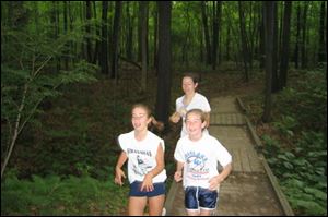 Coach Sarah White, rear, goes on the trail with Sylvania Striders team members McKenzie est, left, and Leah Zellers.