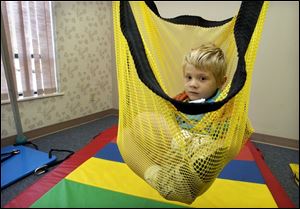Mitchell Sworden, 3, enjoys a ride in a net swing during the 'play' time part of his session at the rehabilitation center.