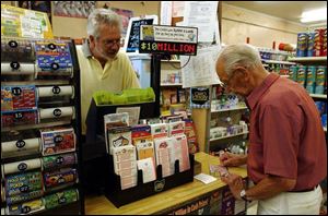 Bill Hudson watches while his father, Robert, tries his luck with a lotto ticket, above. Robert Hudson managed the store, at left, until he retired and his son took it over in 1984. 