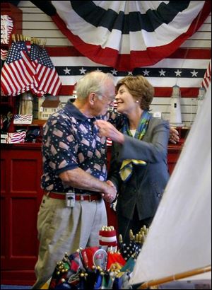 The First Lady hugs Howard Pinkley as she leaves his flag shop. During her stop here, Mrs. Bush credited success of women entrepreneurs to her husband's economic policies.