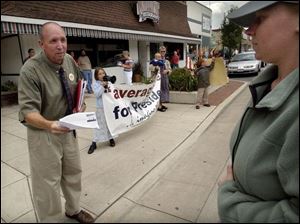REG August 11, 2004 - Presidential candidate Joe Schriner hands campaign literature to a skeptical pedestrian while stumping for votes in Bowling Green with the help of his family, including daughter Sarah, 8, holding banner and megaphone, wife Liz, holding son Jonathan, 1, and son Joseph, 6, right.  Blade photo by Dave Zapotosky  joe11p