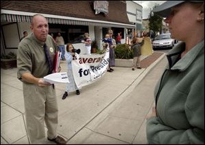 REG August 11, 2004 - Presidential candidate Joe Schriner hands campaign literature to a skeptical pedestrian while stumping for votes in Bowling Green with the help of his family, including daughter Sarah, 8, holding banner and megaphone, wife Liz, holding son Jonathan, 1, and son Joseph, 6, right.  Blade photo by Dave Zapotosky  joe11p