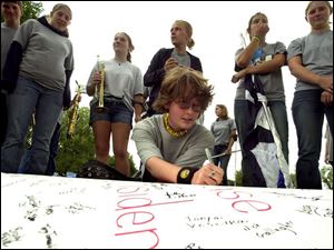 Lake High School sophomore Rebecca Heilman adds her name to a poster advocating adoption of an income tax to fund Lake Local schools. She joined fellow band members in kicking up the effort to have announced cuts in sports and activities scrapped. Lake Local rallies around income-tax drive