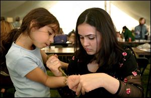 Iman Alhaj, 6, gets a tattoo from Mehuish Durrani at the International Festival at the Islamic Center of Greater Toledo. 