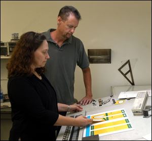 Mary Feasel, left, production manager for Roman/Peshoff, and John Wenberg, press operator at Muir Graphics, Inc., look over advertising materials done for Roman/Peshoff. 