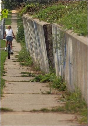 NBR WALL26P 8/16/04 PHOTO BY LORI KING A bicyclist rides past the leaning wall along Glenwood in Rossford.