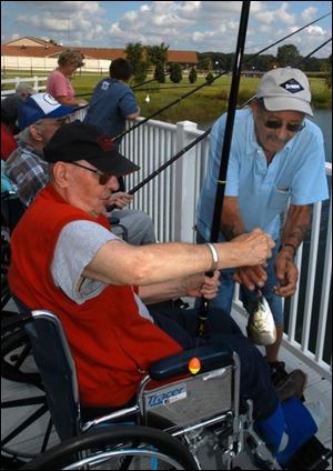 Former commercial fisherman Bill Malaspina helps Paul Lang, a Heartland of Browning resident, land his catch from a pond.