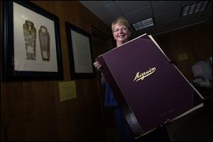 Susan Berryman, director of the Schultz-Holmes Memorial Library in Blissfield, Mich., holds one of four volumes with colored lithographs of ancient Egyptian attractions.
