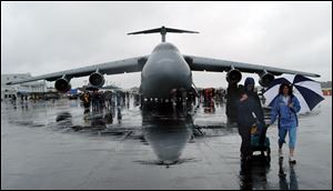 With a C-5 Galaxy Air Mobility Command Plane as a backdrop, Edward and Corey Manuslak of Tecumseh and sons Lucas and Noah weather the rain at the Meijer Toledo Air Show.
