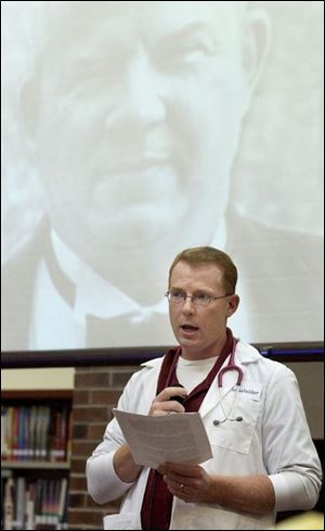 Craig Householder portrays his father, the late Dr. Floyd Frederick Householder, whose image is projected on the screen behind him, during the Oak Grove Living History Day.