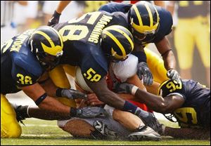 Michigan defenders Scott McClintock (36), Roy Manning (58), Leon Hall and Pierre Woods (99) smother Miami quarterback Josh Betts. The Wolverines forced seven turnovers.
