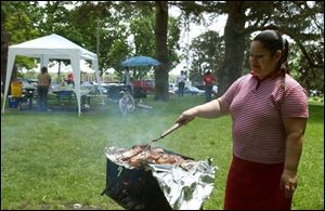 Maritza Santiago grills the food at a Ponce family picnic held at Walbridge Park on Memorial Day.