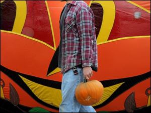 ROV pumpkin 01 - Mike Glenn, an employee of Schweizer's Fruit Farm in Oregon, Ohio, carries a pumpkin as he re-stocks the shelves for the fall season. Allan Detrich/The Blade