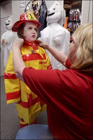 Makenna McNutt, 5, is stoic during a fitting by Costume Holiday House's Ina Blazer for a firefighter costume.