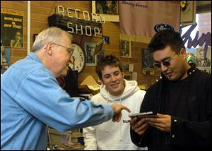 William Schurk, BGSU sound recording archivist, left, shows the John Kerry CD cover to Mike Toth, center, and Aaron Kato.