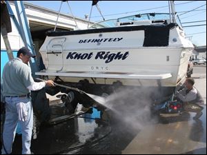 Rov boatout 3 Trevor Coleman of Toledo, sprays off his 27 foot boat at the Ottawa river yacht club as Harry Philabaum, with  Counterman marine adjust hoist . blade photo by herral long 10/6/2004