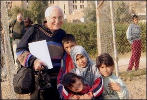 Bishop Thomas Gumbleton, shown visiting with Iraqi children in Baghdad in January, will speak in Tiffin on Thursday.