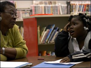 ROV Homework helpers Eboni Howell, six of Toledo, trys to decide what she will draw as part of her first grade homework assignment while homework helper Odell Chancy, a retired school teacher of 33 years, gives her some ideas. Chancy, volunteering as a homework helper for the last three years, is available at the Kent branch of the Toledo/Lucas County Public Library. Other helpers are available at branches throughout the week. Blade photo by Luke Wark