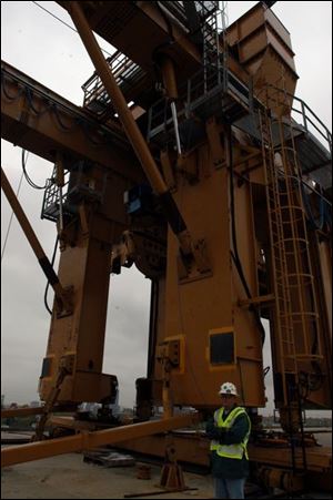 Bob Lindsey stands guard at the new anchor devices, left center, installed on the existing crane to prevent the legs of the crane from lifting up or shifting sideways.