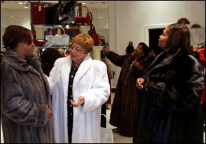 PERFECT FIT: From left, Cheryl Slack, Leola Haynes, and Clara Petty try on furs as Julia Holt, background, looks at accessories at Roth Furs downtown.