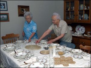 Marge, left, and Alta Grieser set the table in their duplex for an auctioned dinner.