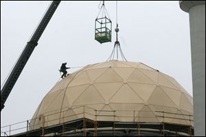 A worker removes the ropes that were used to lift the dome.