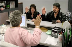 Denise Killoran and her fiance, Craig Stanley, of Riverview, Mich., take an oath from Susan Smith in the marriage license office at the Lucas County Courthouse. Michiganians account for about half of those seeking marriage licenses in Lucas County.