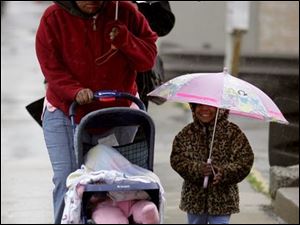 ROV November 24, 2004 - Rachelle Betts and her children, Tanajah Betts, 10 months old, and Taniya Williams, 3, try to stay dry while heading to a bus stop on Erie Street in downtown Toledo Wednesday morning.  Blade photo by Dave Zapotosky