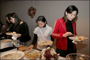 Taiwanese students Kitty Liao, in white, and Emma Huang, right, partake in the university holiday meal for foreign students.