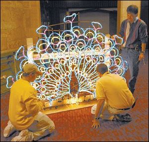 Mike Briggs, Jeff Goodman, and Larry Starkey, from left, work on a light fixture that will be mounted atop a parade float. 
