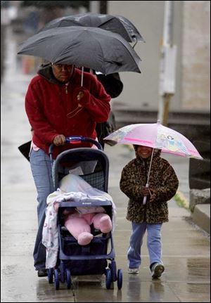 ROV November 24, 2004 - Rachelle Betts and her children, Tanajah Betts, 10 months old, and Taniya Williams, 3, try to stay dry while heading to a bus stop on Erie Street in downtown Toledo Wednesday morning.  Blade photo by Dave Zapotosky