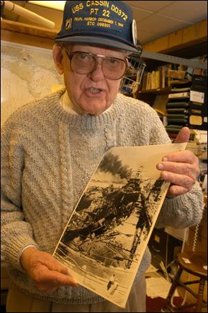 Tom Child, holding a photo of his ship, was a torpedo officer aboard the USS Cassin when the Japanese attacked Pearl Harbor. Mr. Child, of Findlay, is among the survivors who want to remind younger generations of the tragedy.