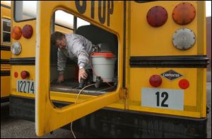 Daryl Franz, a North Central school board member, sweeps broken glass from one of the buses that was vandalized. So far, damage is estimated in the thousands of dollars.