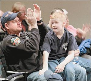 Toledo firefighter Sterling Rahe applauds the remarks of others during last night's Toledo City Council meeting as his son, Jon, takes in the scene.