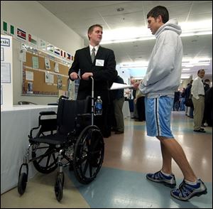 Engineering student Doug Stricker, left, shows Doug Martz the wheelchair extension push handles his team designed. 