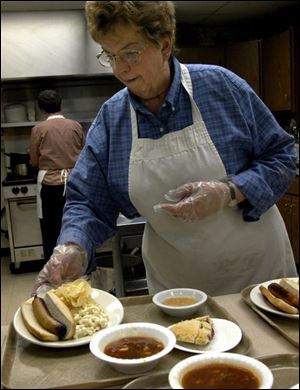 Marilyn Lazenby of Findlay sets down a plate of food as she gets ready to serve dinner at City Mission in Findlay. Ms. Lazenby has been the full-time cook at the mission for five years.