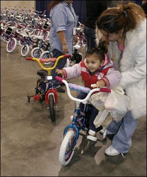 Analicia Jimenez, 2, and her mother, Christina Rivera, test the toddler's new bike at the SeaGate Convention Centre. Cathedral of Praise gave away 225 bicycles to families in need.