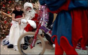 Dominique Guerrero, 7, is all smiles as a Santa's assistant rolls out her new bicycle at Friday's Christmas party.