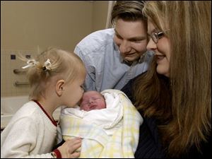 CTY newbaby02p Emily Bruhl, 3, left,  kisses her new baby brother Joshua Bruhl, as dad Steven Bruhl, and mom Laurel Bruhl look on at St. Anne's Hospital on Saturday 1/1/05.  The Blade/Dave Zapotosky