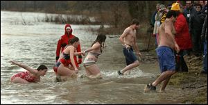 A Waterville rescue worker oversees swimmers taking the annual polar bear dip in the Maumee River. The event, which draws the brave and the foolhardy, has heralded the new year in the village since the 1920s. About 100 swimmers participated yesterday. The water was 33 degrees and the air was only slightly warmer.