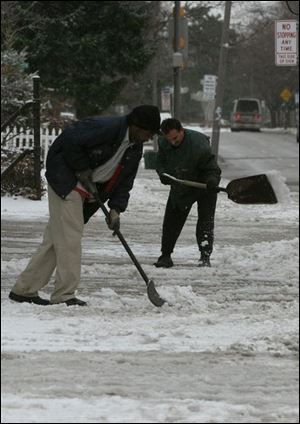 John Smith, left, and Adnan Abuhamad shovel outside the Glendale Shops on Glendale at the Anthony Wayne Trail.