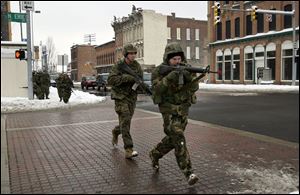 Marine reservists cross Erie Street at Monroe Street, weapons at the ready. The M-16A2 rifles carried only blanks. The reservists also received classroom instruction during the exercise.