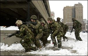 Reservists of the Weapons Company, 1st Battalion, 24th Marines test their urban fighting skills along a downtown street. the blade/dave zapotosky Curious and surprised spectators watch the Marine exercises downtown. James Eggleston of Elyria used his video camera to capture the military training for later viewing.