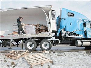 Aaron Myshock unloads orange juice from a crashed tractor-trailer rig on U.S. 23 near Sterns Road.
