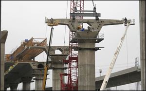 Construction crews using ground-based cranes hoist one of the segments of the new I-280 bridge to its pier-top position.